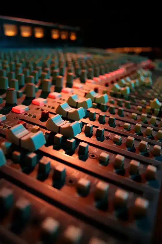 Faders d’une console audio sous éclairage de studio